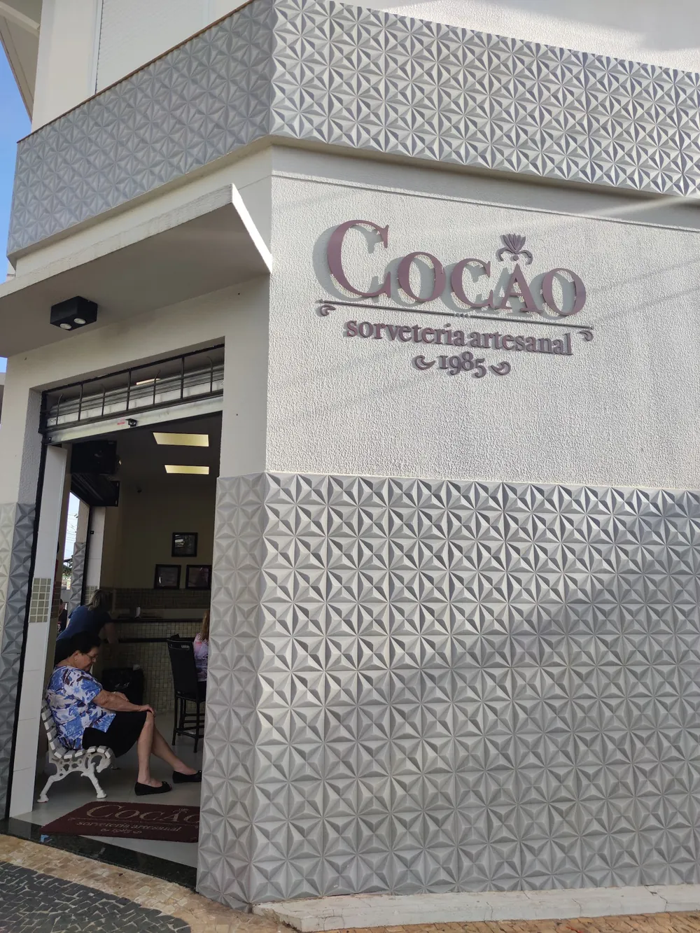 Fachada da Cocão com o letreiro sorveteria artesanal 1985 e o banco na calçada